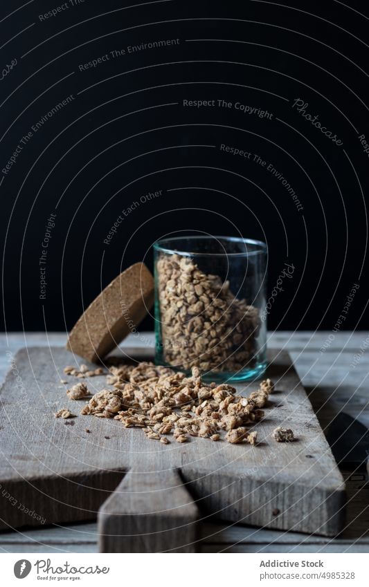 Ein Glas mit Müsli auf dem Schneidebrett Walnussholz Holzplatte hölzern zerkleinernd Schneiden satt frisch Lebensmittel lecker Gesundheit natürlich Diät Dessert