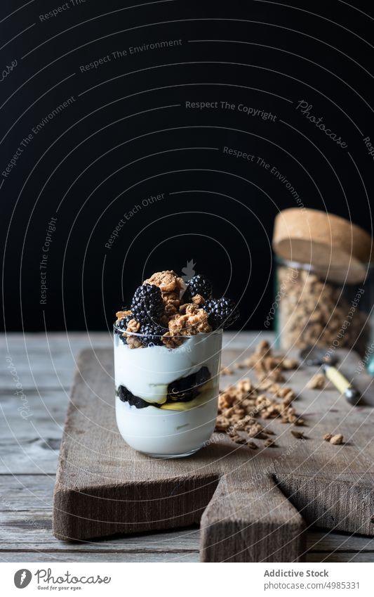 Glas voll Walnuss-Granola mit Heidelbeeren Blaubeeren Müsli Walnussholz Joghurt mischen Holzplatte hölzern Schneiden zerkleinernd reif Haufen frisch Beeren