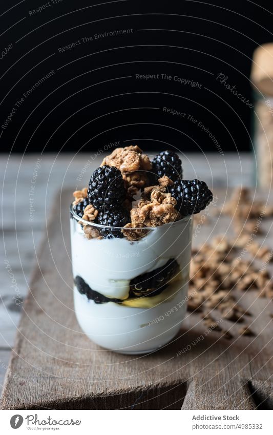 Glas voll Walnuss-Granola mit Heidelbeeren Blaubeeren Müsli Walnussholz Joghurt mischen Holzplatte hölzern Schneiden zerkleinernd reif Haufen frisch Beeren