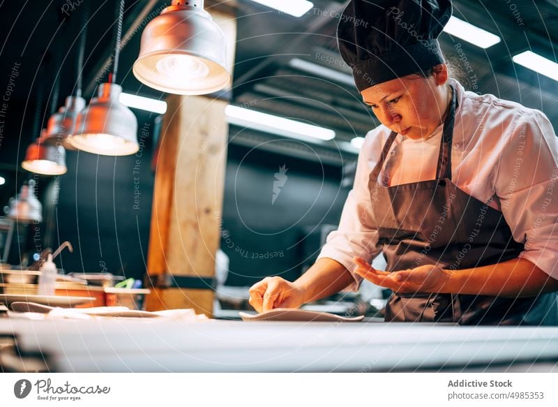 Frau serviert Gerichte in Restaurantküche Küchenchef dienen vorbereiten Lebensmittel Speise professionell Gastronomie Küchengeräte wirtschaftlich Uniform modern