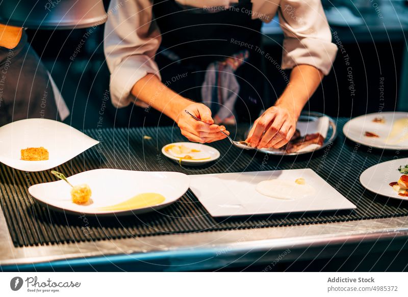 Kropfenkoch serviert Gerichte Küchenchef eingießen Saucen Speise Garnierung Platten Lebensmittel Restaurant Mahlzeit professionell Feinschmecker Uniform lecker