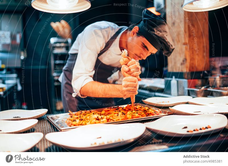 Profikoch serviert Essen auf Tellern Küchenchef dienen Saucen eingießen Mahlzeit Gerichte Garnierung Gastronomie Lebensmittel Restaurant wirtschaftlich Speise