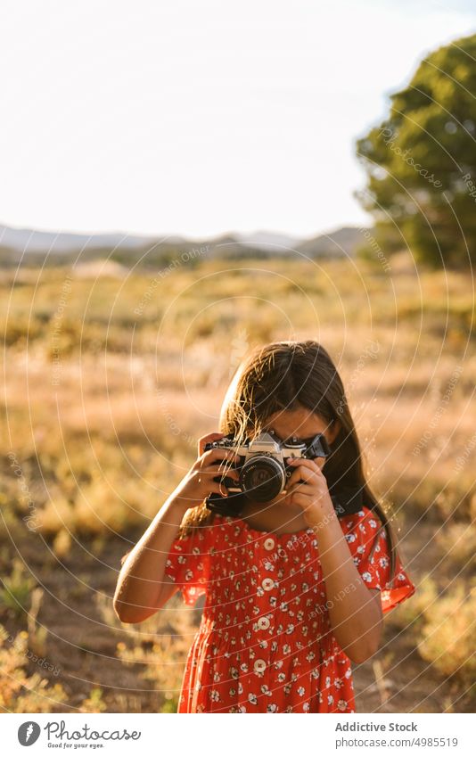 Kleines Mädchen fotografiert eine Landschaft an einem sonnigen Tag fotografierend Sommer Feld Natur Fotokamera Fotografie Glück Wiese schön bezaubernd rot Kind