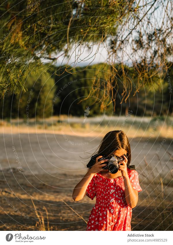 Kleines Mädchen fotografiert eine Landschaft an einem sonnigen Tag fotografierend Sommer Feld Natur Fotokamera Fotografie Glück Wiese schön bezaubernd rot Kind