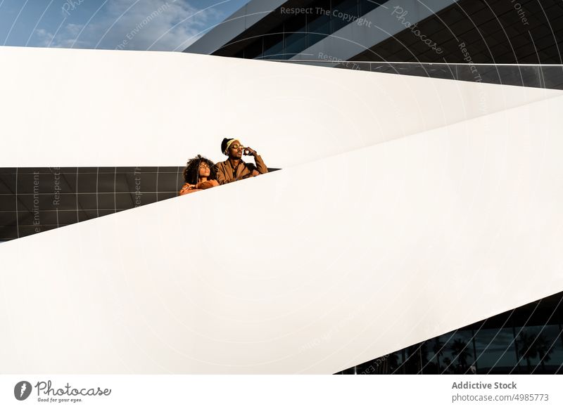 Träumendes trendiges Paar auf einer Treppe bei Sonnenuntergang in der Stadt Streetstyle Architektur träumen urban modern trendy Stil ethnisch schwarz