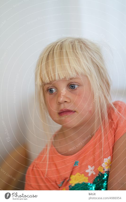 Träumen. Natürliches, blondes Mädchen vor hellem, neutralen Hintergrund, lacht in die Kamera. Kind, Mädchen mit leuchtenden Augen. Lustiges, witziges Portrait. Kindheit, Glück, Tagtraum, verträumt. Schöne Kindheit. Kind, Zähne, Mund. Frech, verschmitzt Spa