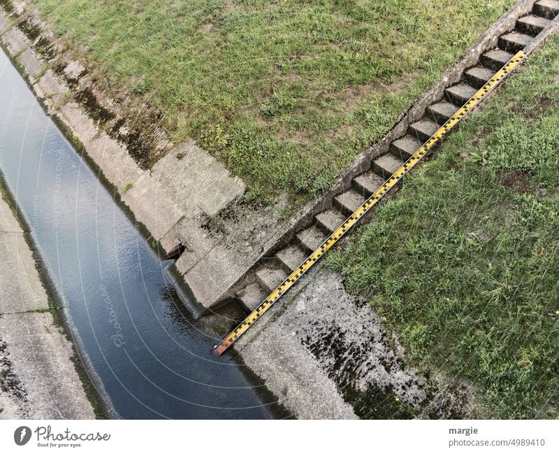 Wassernotstand an einem Fluss Niedrigwasser messen Außenaufnahme Meßlatte Treppe flach flaches Wasser Umwelt Klimawandel Flussufer Natur Betonboden Betonmauer