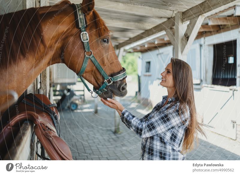 Frau mit ihrem Pferd in den Ställen Ranch Sattel Pferdestall eine Person Menschen Erwachsener Scheune Tiere Ländliche Szene Dompteur Pflege Bauernhof Hobby