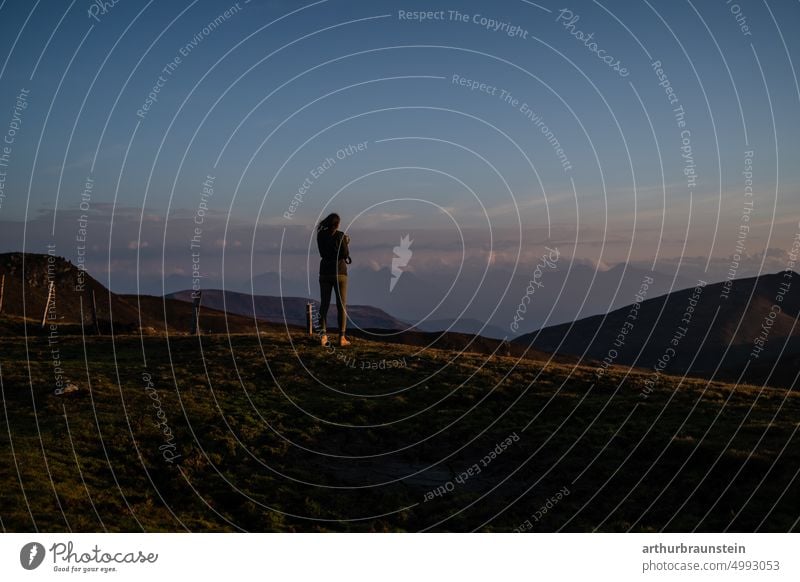 Junge Frau mit Fotoapparat bei Sonnenaufgang am Berg unter blauem Himmel berge bergpanorama bewegung draussen fotografie fotografieren freiheit freizeit früh