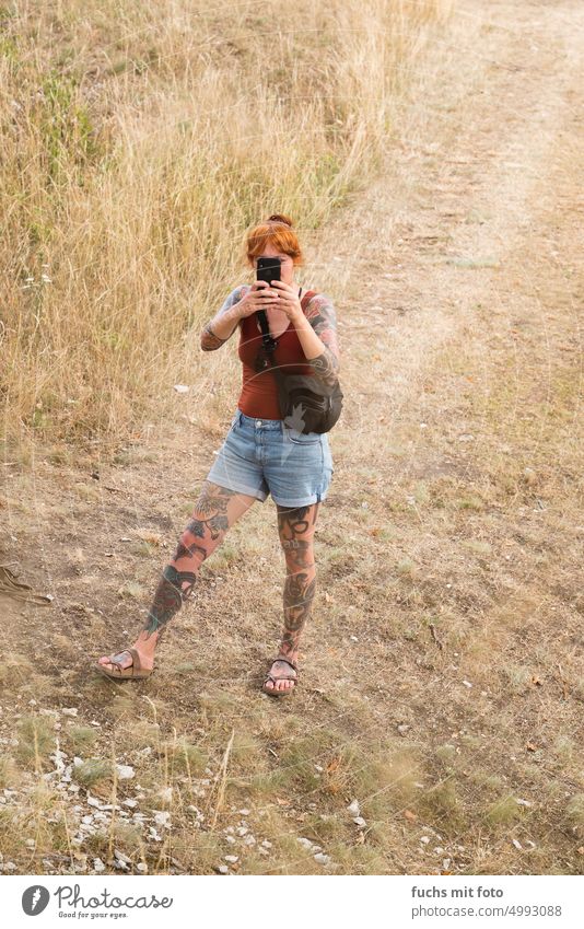 Start tätowierte Frau mit einem Smartphone. Tattoo Tattoos beine foto Handyfoto Porträt handyfoto tätowiertes Mädchen bildhübsches Mädchen hübsche Frau Mensch