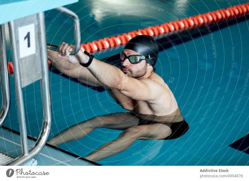 Schwimmer mit Schwimmbrille und Kappe beim Training im Schwimmbad Athlet Sport Dehnung Schwimmsport Übung Aufwärmen Schutzbrille Pool Mann Sportler Klotz