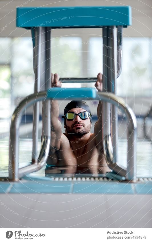 Schwimmer mit Schwimmbrille und Kappe beim Training im Schwimmbad Athlet Sport Dehnung Schwimmsport Übung Aufwärmen Schutzbrille Pool Mann Sportler Klotz