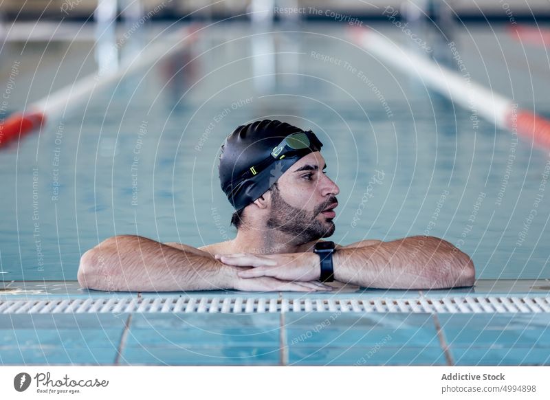 Schwimmer mit Schwimmbrille lehnt am Beckenrand sich auf die Hand lehnen Schutzbrille maskulin Mann Porträt Athlet Sport Macho müde Pool Accessoire Sportler