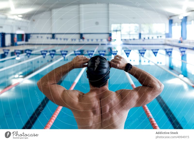 Nicht erkennbarer muskulöser Sportler, der auf einem Block am Pool sitzt Training Schwimmsport Klotz Mann Schwimmer Podest vorbereiten professionell