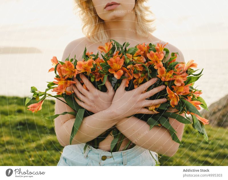 Frau mit Blumen am Meer MEER Deckbrust Ufer Sonnenuntergang oben ohne Natur Abend Sommer Aviles Asturien Spanien blond Blüte Saison Pflanze Seeküste Wasser