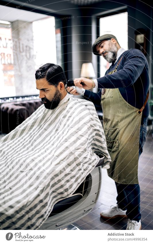 Ein Kunde erhält einen Haarschnitt in einem modernen Friseursalon Klient Salon hispanisch Pflege ethnisch Kap professionell Männer Dienst männlich Frisur