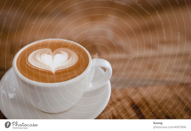 Cappuccinotasse mit Latte Art Herz auf Holztisch. Kaffee Tasse Tisch Tischplatte Aroma Barista Getränk Getränke Unschärfe Holzplatte braun Braunton Café Cafés