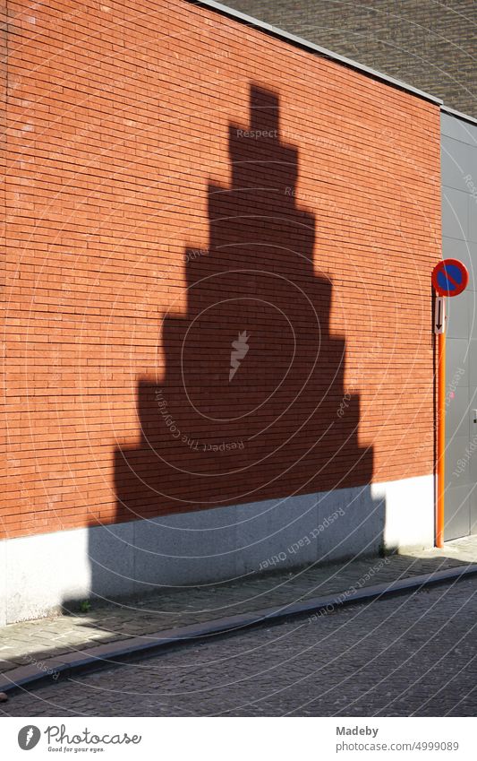 Schatten eines historischen Treppengiebel auf einer Fassade aus rotbraunem Backstein im Sonnenschein in den Gassen der Altstadt von Brügge in Westflandern in Belgien