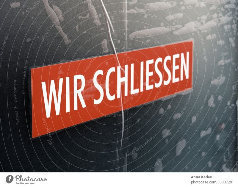 Ein rotes "Wir schliessen " Schild mit weisser Schrift klebt auf einem Schaufenster Hinweisschild Schließung von Wirtschaftskrise Insolvenz Geschäftsaufgabe