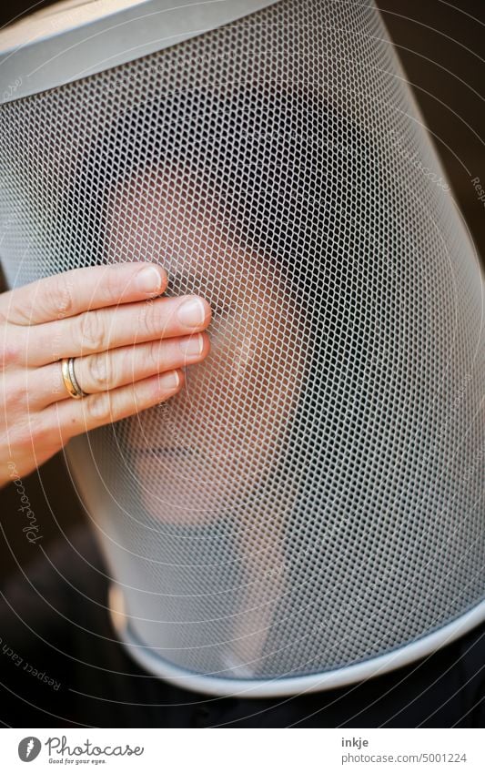 Frau mit Metallkorb über dem Kopf hält sich die Hand vor die Augen Augen geschlossen Nahaufnahme seltsam Mimik Trauer Isolation Frust Gesicht Traurigkeit