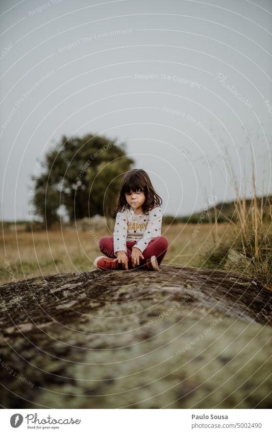 Niedliches Mädchen sitzt auf einem Felsen Kind Kindheit 3-8 Jahre Sitzen Feld Natur Kindheitserinnerung Lifestyle Freizeit & Hobby Mensch Außenaufnahme