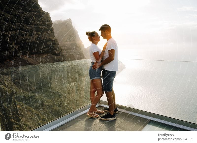 Junges Paar auf einem Aussichtspunkt vor vulkanischen Klippen und dem Meer Liebe Flitterwochen jung Sonnenuntergang Kaukasier Textfreiraum Steine