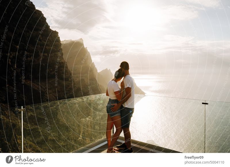 Junges Paar auf einem Aussichtspunkt vor vulkanischen Klippen und dem Meer Liebe Flitterwochen jung Sonnenuntergang Kaukasier Textfreiraum Steine