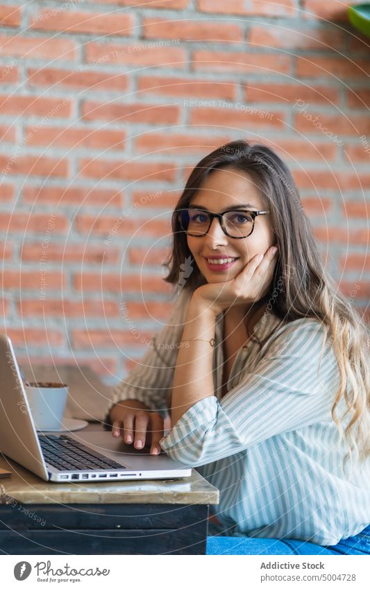 Lächelnde Freiberuflerin mit Laptop in einem Café Frau freiberuflich benutzend Projekt Glück Daten Freude abgelegen Telearbeit Tisch froh jung smart lässig