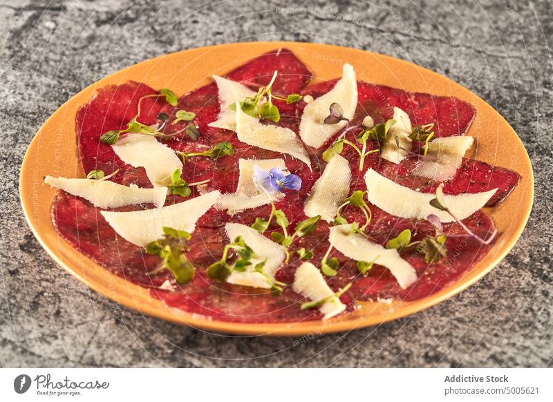 Carpaccio al parmigiano auf einem Teller Kalbfleisch Scheibe Speise Restaurant Käse Parmesan sprießen Portion Lebensmittel Erdöl Zitrone schwarzer Pfeffer