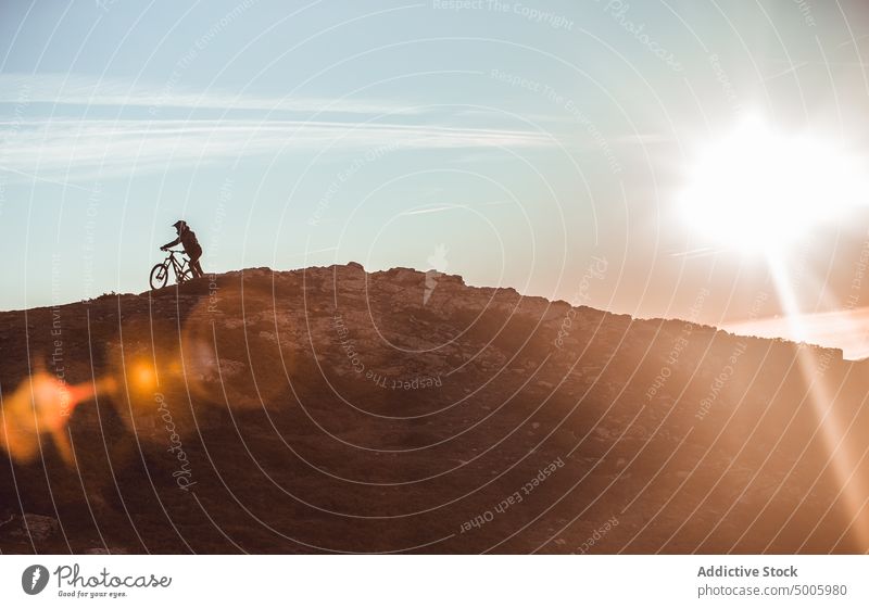 Mann fährt mit dem Fahrrad auf einem Hügel Reiten Schutzhelm extrem Sport Berge u. Gebirge Top Typ Himmel Sonne Sonnenschein männlich Sicherheit