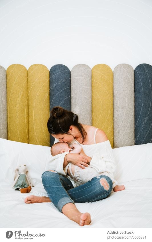 Glückliche Mutter, die ihr ruhiges Baby füttert, während sie sich zu Hause im Bett entspannt Futter Säugling Kind Eltern essen heimwärts Mama Harmonie Komfort