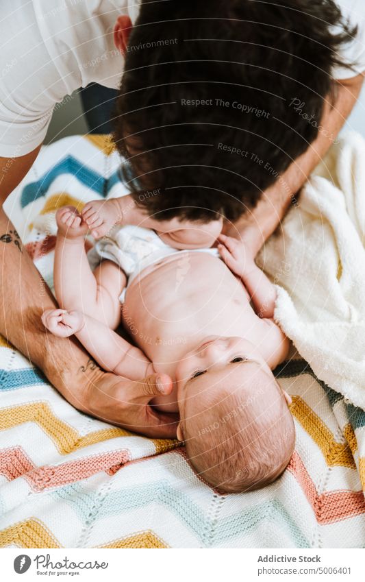 Crop Vater Kleidung neugierig Baby in warmen Bademantel nach dem Baden in hellen Schlafzimmer sich[Akk] entspannen Dressing frisch Hand Eltern Elternschaft Bett