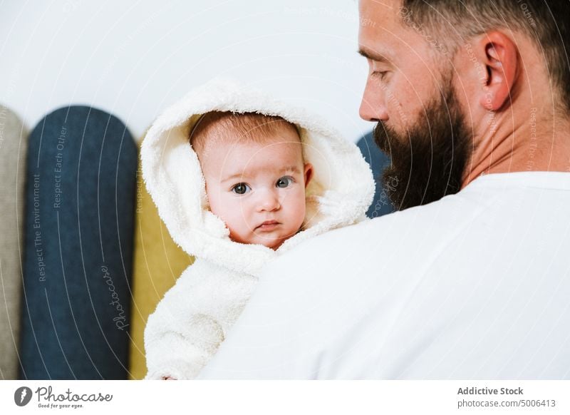 Ruhiger erwachsener Vater trägt süßes Baby auf Händen zu Hause Eltern Papa heimwärts Kind Waschen frisch Dusche Bademantel Säugling neugierig Partnerschaft