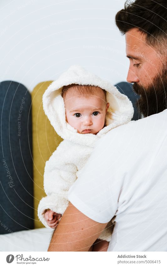 Ruhiger erwachsener Vater trägt süßes Baby auf Händen zu Hause Eltern Papa heimwärts Kind Waschen frisch Dusche Bademantel Säugling neugierig Partnerschaft