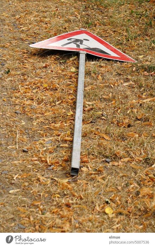 auf dem vertrockneten Rasenboden liegendes Verkehrsschild  - Vorsicht Baustelle - / Baustellenschild Verkehrszeichen VZ 123 Vandalismus Abbruch Bauarbeiten