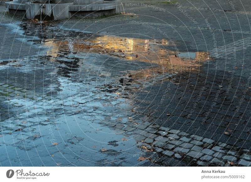 Zur goldenen Stunde spiegelt sich ein Haus in einer Pfütze auf dem Asphalt Spiegelung Reflexion & Spiegelung goldenes Licht goldene stunde glänzend