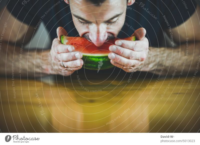 genüsslich in eine Wassermelone beißen Obst essen Vitamine Mann lecker Ernährung gesund Mund abbeißen Lebensmittel saftig Fitness Gesunde Ernährung sportlich