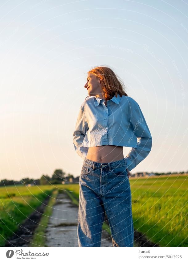 fröhliches Mädchen in der Abendsonne lachen Glück sonnen teenager glücklich Freude unbeschwert Hemd Jeans bauchfrei Lebensfreude jung Jugend rote Haare lächeln