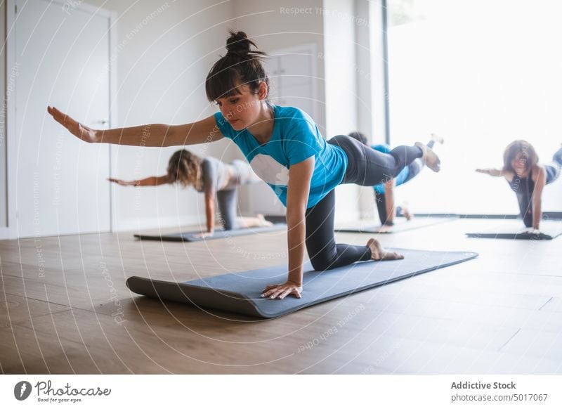 Junge Frau in der Yoga-Pose Vyaghrasana Ausbilderin Menschengruppe Tiger-Pose vyaghrasana beweglich Asana verdrehen Klasse Dehnung üben Zusammensein Unschärfe