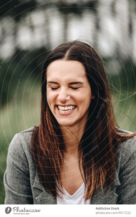 Lächelnde Frau mit langen Haaren und geschlossenen Augen stylisch Park charmant Menschliches Gesicht attraktiv heiter Glück Mode Erwachsener elegant lässig