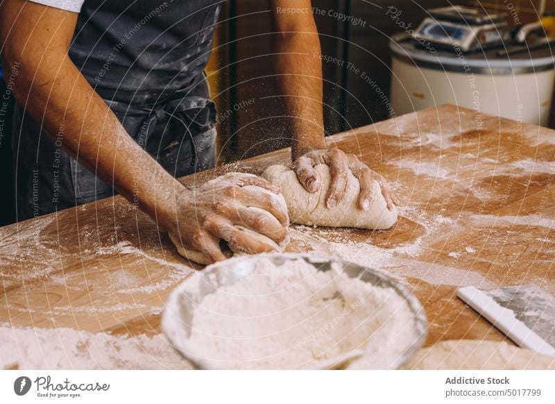 Anonymer Mann, der in einer Bäckerei Teig formt Teigwaren Koch Prozess Form vorbereiten Tisch Uniform männlich Küche Lebensmittel hölzern Gebäck frisch