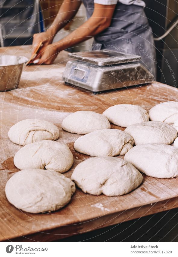 Erntekoch wiegt Teig Bäckerei Gewicht Teigwaren Koch Mann roh Skala Prozess Brot männlich vorbereiten hölzern Tisch Küche kulinarisch frisch Bestandteil Mehl