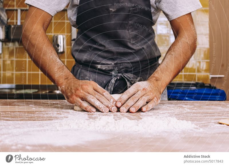 Anonymer Mann, der in einer Bäckerei Teig formt Teigwaren Koch Prozess Form vorbereiten Tisch Uniform männlich Küche Lebensmittel hölzern Gebäck frisch