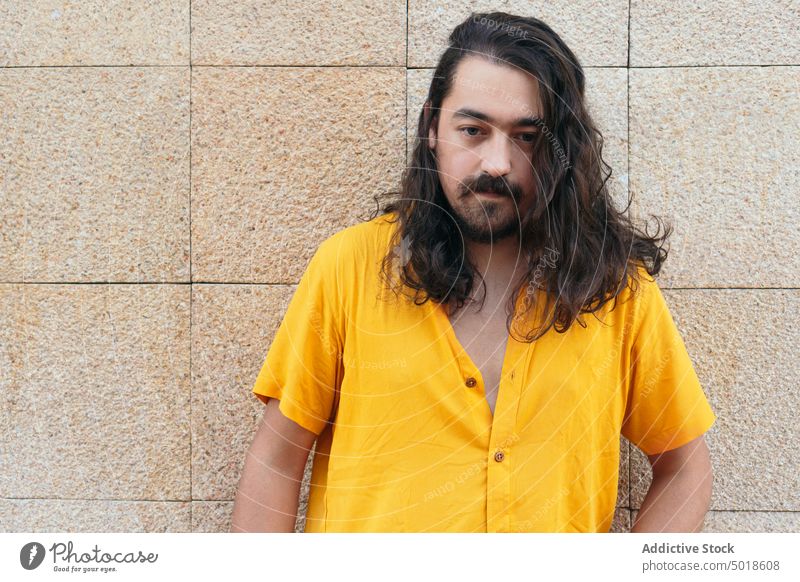 Portrait os stilvollen Mann mit langen Haaren in der Stadt Hipster lange Haare Vollbart Stil Vorschein gewelltes Haar Sommer Outfit hell männlich