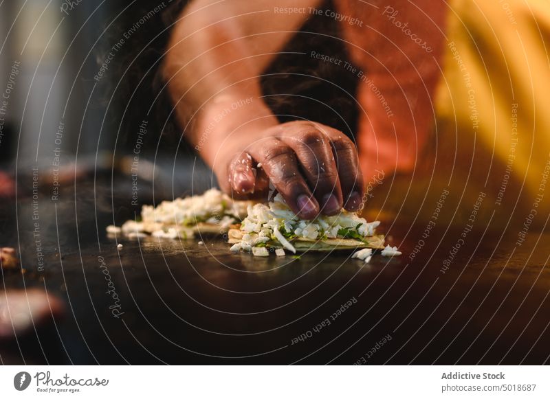 Crop-Koch bei der Zubereitung leckerer Tacos in der Restaurantküche Küchenchef vorbereiten Käse mexikanisches Essen Job Straßenessen geschmackvoll Tisch