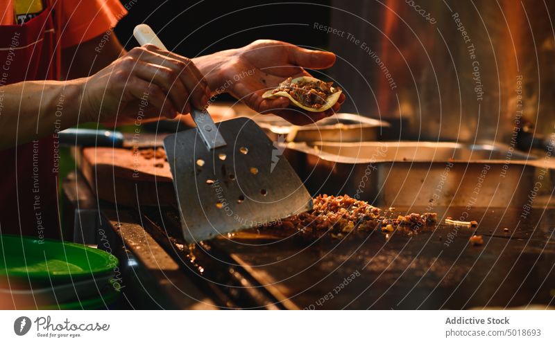 Crop-Koch bei der Zubereitung leckerer Tacos in der Restaurantküche vorbereiten Straßenessen mexikanisches Essen Rindfleisch Tortilla braten Küche Arbeit