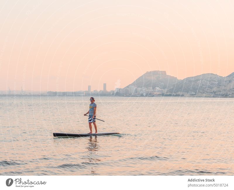 Mann mit Paddel auf Surfbrett auf hoher See Surfen MEER Meer Wasser aktiv Urlaub Sommer männlich Lifestyle extrem winken Abenteuer Erholung Athlet Sommerzeit