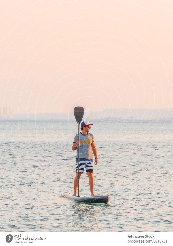 Mann mit Paddel auf Surfbrett auf hoher See Surfen MEER Meer Wasser aktiv Urlaub Sommer männlich Lifestyle extrem winken Abenteuer Erholung Athlet Sommerzeit