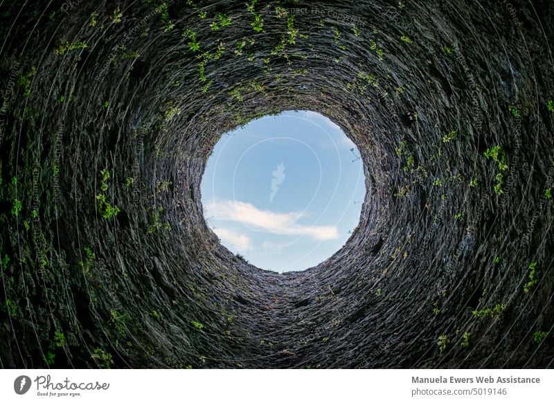 Blick nach oben durch die runde Öffnung eines steinernen Turms turm tunnel tunnelblick öffnung licht am ende des tunnels himmel tageslicht dunkel dunkelheit