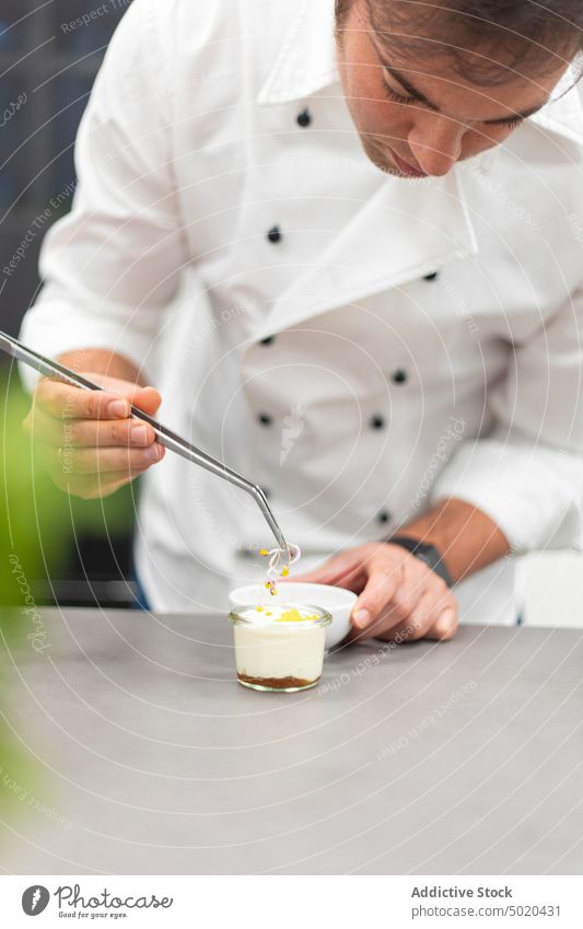 Profikoch benutzt Metallwerkzeug beim Kochen Küchenchef Essen zubereiten professionell benutzend Mann vorbereitend Speise Restaurant fokussiert ausgefallen